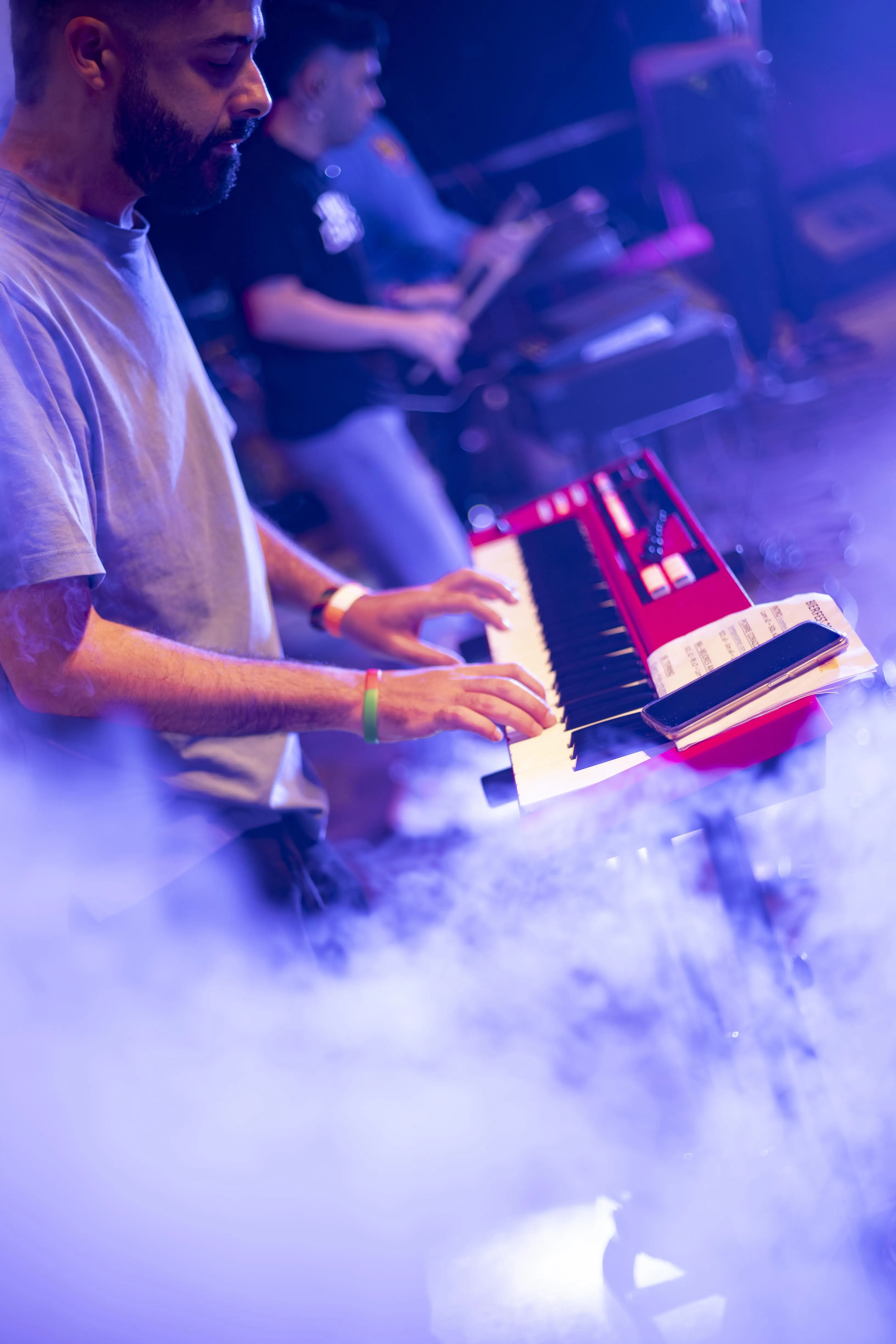 Tecladista de Meraki Music durante un show en vivo con luces y humo en el escenario